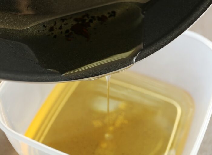 Pouring oil from a pan to a container for proper disposal.