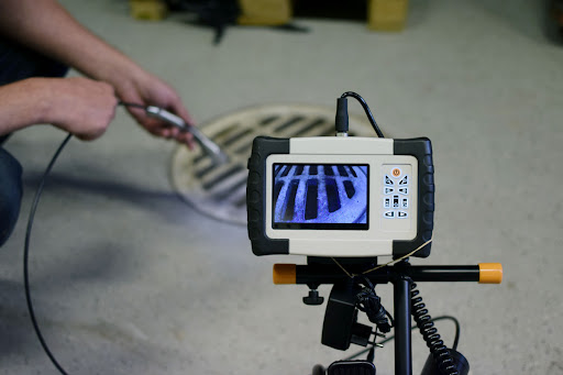 A technician inserting a sewer inspection camera into a pipe.