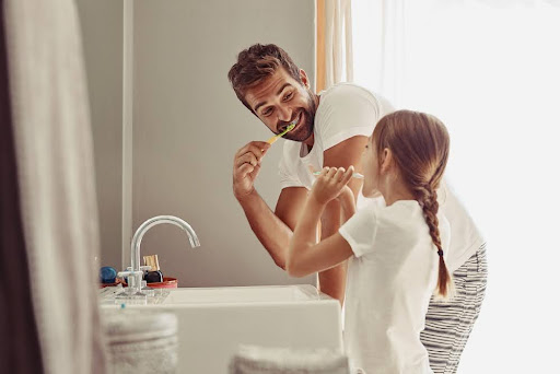 A father and daughter brushing their teeth.