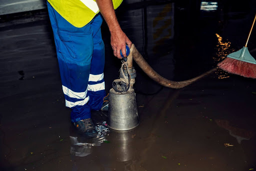 Same Day Plumbing worker installing sump pump in flooded basement